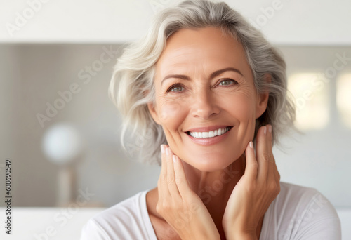Closeup of happy smiling beautiful 50s middle aged woman looking at camera touching face. Aging beauty, skincare treatment cosmetics concept