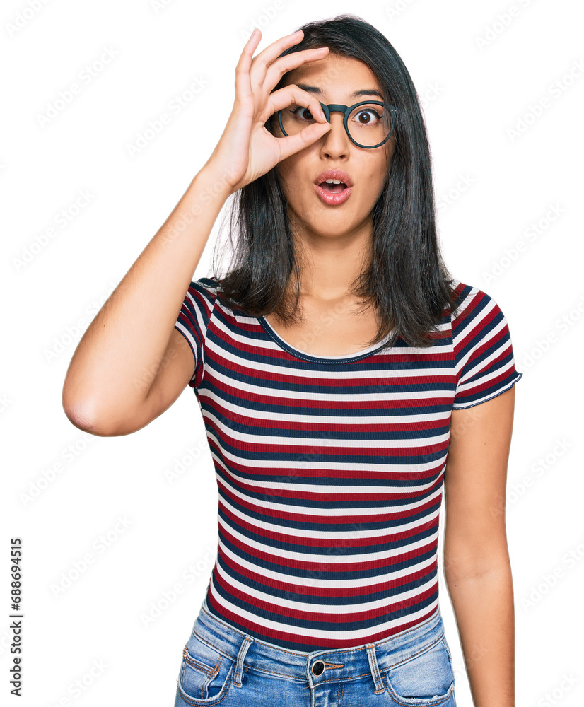 Beautiful asian young woman wearing casual clothes and glasses doing ok gesture shocked with surprised face, eye looking through fingers. unbelieving expression.