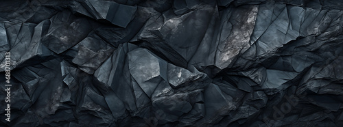 A dark blue rock face, surface background with jagged edges and crevices.  photo