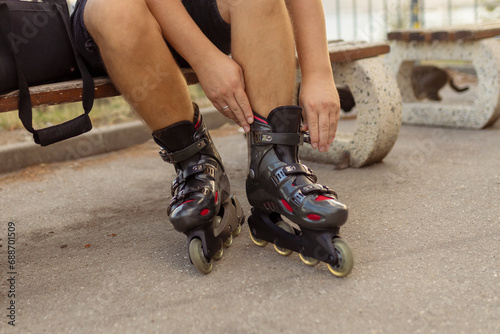 Legs of young man putting on roller skates in the park