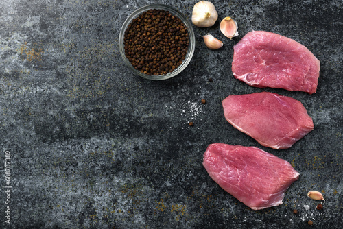 Raw pork meat with spices on black background.