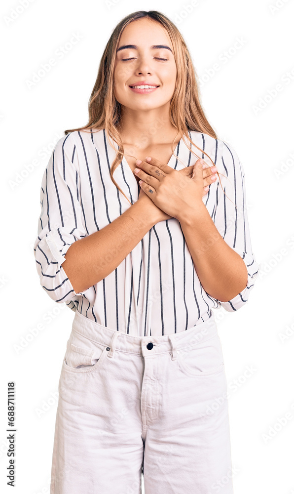 Young beautiful blonde woman wearing casual clothes smiling with hands on chest with closed eyes and grateful gesture on face. health concept. Young beautiful blonde woman wearing casual clothes smiling with hands on chest with closed eyes and grateful gesture on face. health concept.