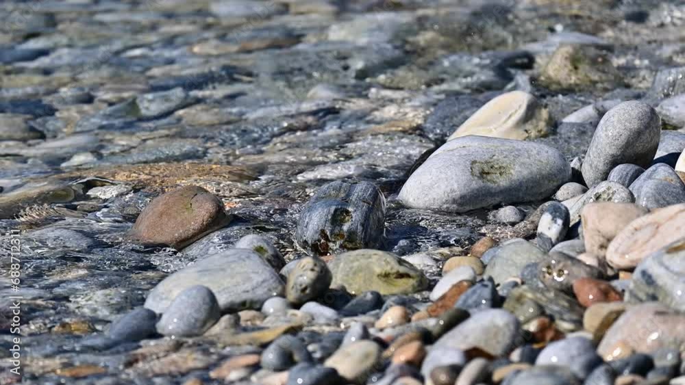 Clear transparent water of the Mediterranean shore flowing over colorful little stones on a beach in Samos Clear transparent water of the Mediterranean shore flowing over colorful little stones on a beach in Samos