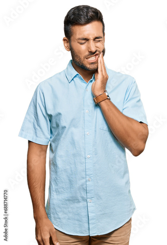 Handsome hispanic man wearing casual clothes touching mouth with hand with painful expression because of toothache or dental illness on teeth. dentist © Krakenimages.com