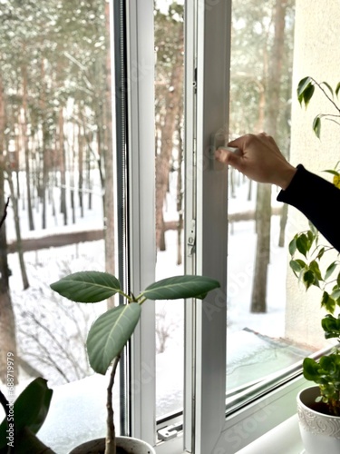 Male person hand opening plastic window for ventilation in winter time
