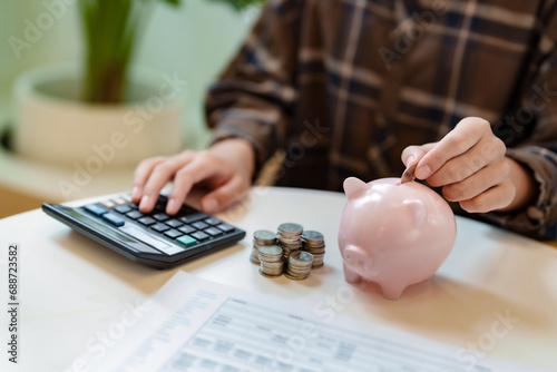 Close up hand putting coin on pink piggybank, saving and money management .