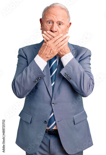 Senior handsome grey-haired man wearing elegant suit shocked covering mouth with hands for mistake. secret concept.