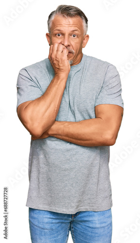 Middle age grey-haired man wearing casual clothes looking stressed and nervous with hands on mouth biting nails. anxiety problem.