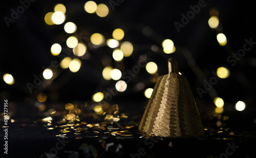 Golden bell on a bokeh background. Black photo. Copy space. 