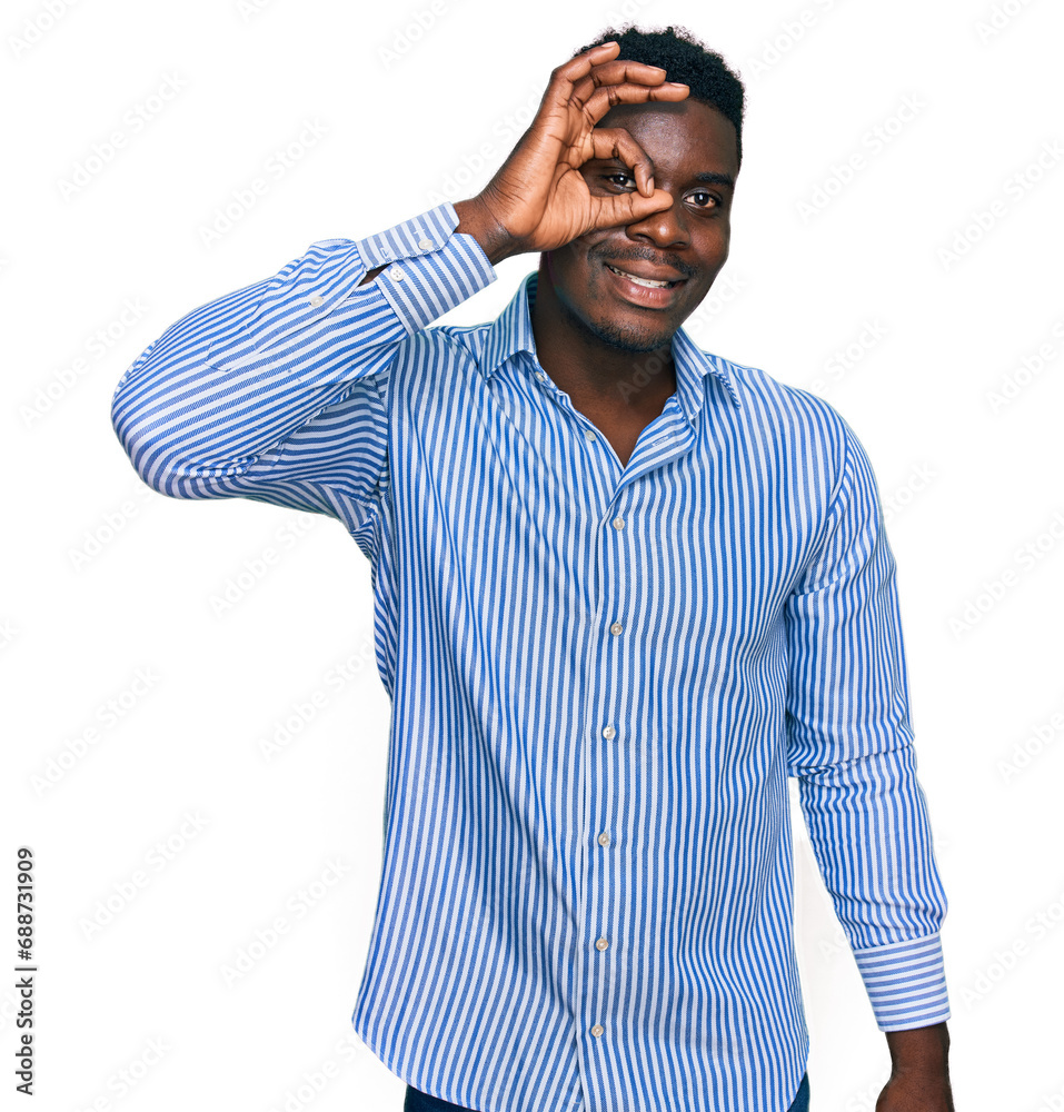 Fototapeta premium Handsome business black man wearing casual striped t shirt smiling happy doing ok sign with hand on eye looking through fingers