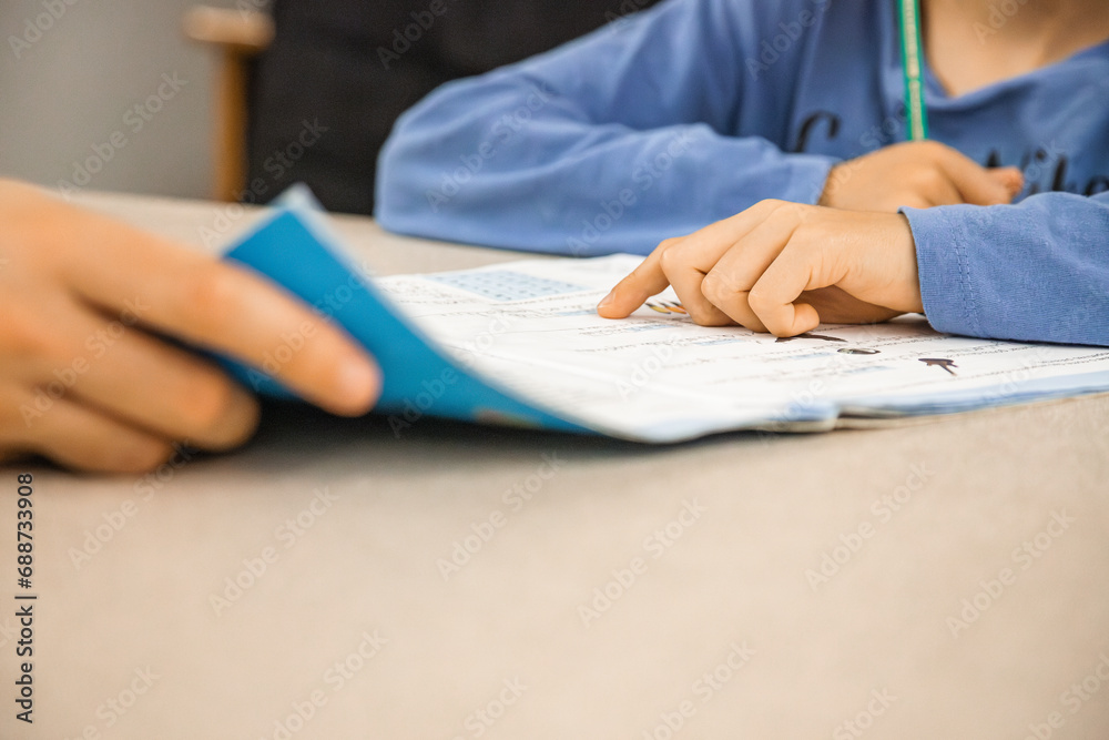 Caucasian elementary school child doing homework at the end of the school day with parental help and support. Close up and copy space.
