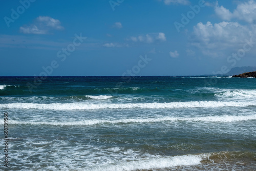 Greek ripple dark sea water, splashing white foam, blue sky background, copy space. Ad template