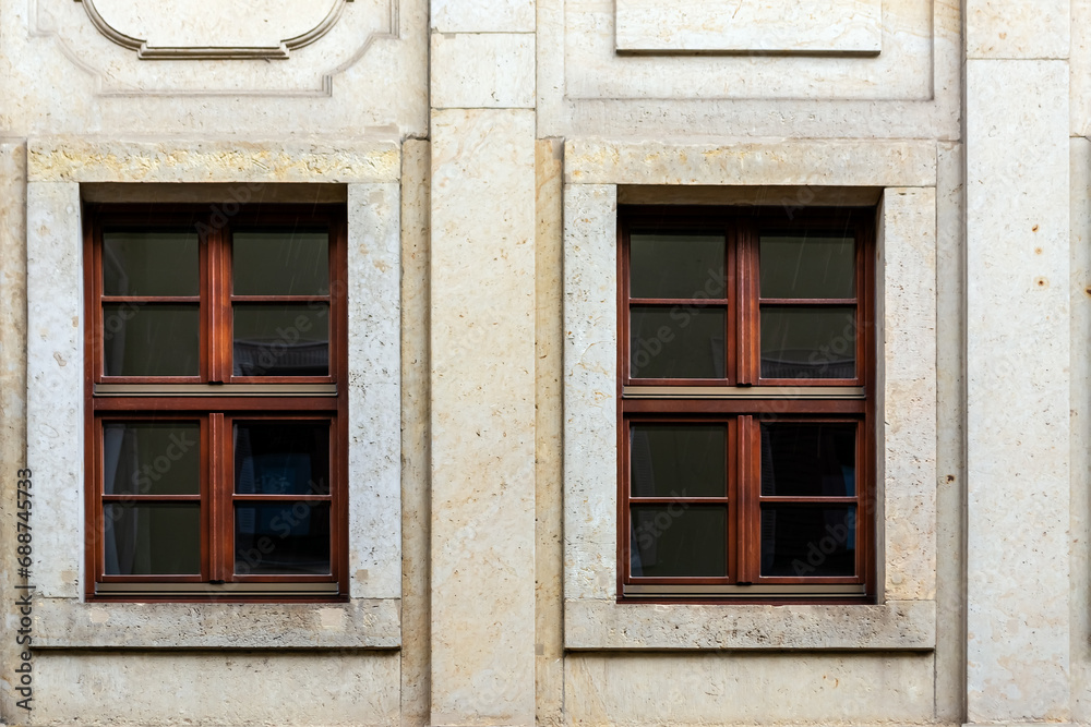 Two rectangular windows with a brown frame on the background of a beige tile wall. From the Windows of the world series.