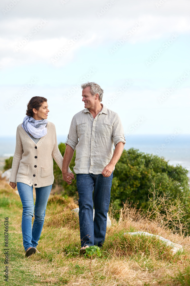 Old couple, walking and holding hands in nature on holiday, vacation or support in retirement. Love, man and woman with conversation, care or happiness in marriage together on grass at beach or park Old couple, walking and holding hands in nature on holiday, vacation or support in retirement. Love, man and woman with conversation, care or happiness in marriage together on grass at beach or park