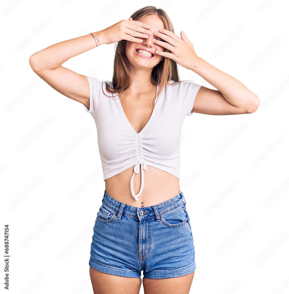 Young beautiful blonde woman wearing casual white tshirt covering eyes with hands smiling cheerful and funny. blind concept.
