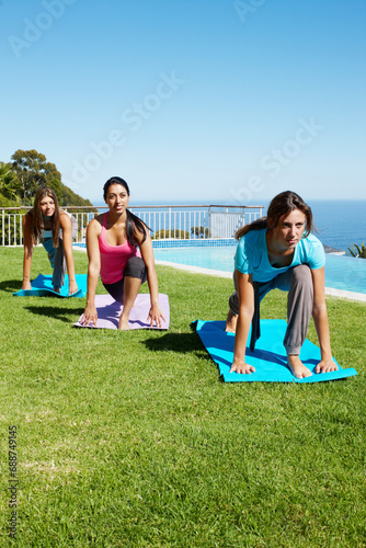 Ocean, yoga and group of women on grass together for fitness, exercise or mindfulness resort. Nature, pilates and happy friends at outdoor holistic health retreat for wellness, balance and sunshine.