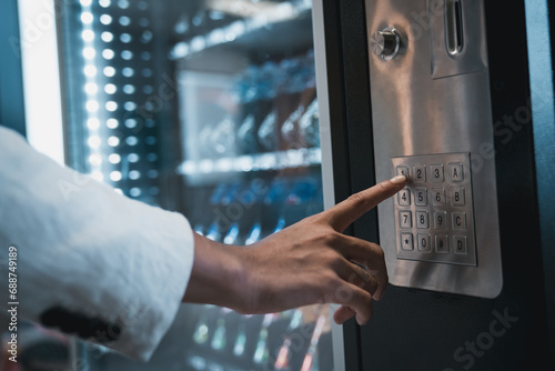 Close up hand of woman pushing button on vending machine for choosing a snack or drink. Small business and consumption concept. photo