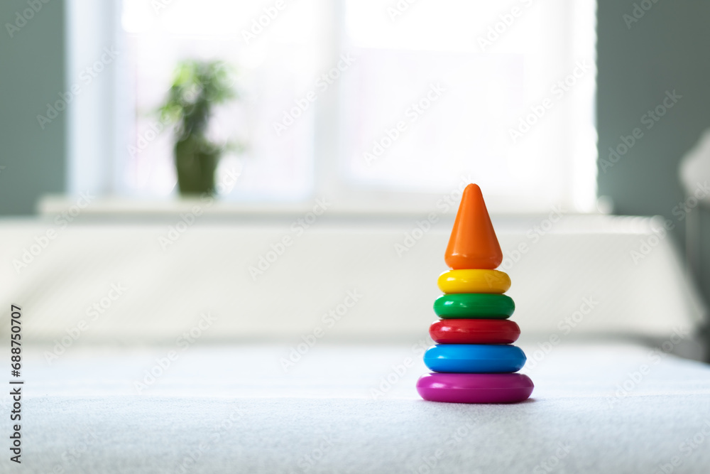 Multi-colored plastic pyramid toy in child playing room. Happy childhood concept - obrazy, fototapety, plakaty 