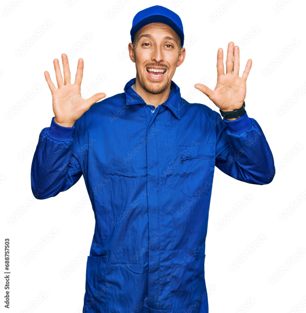 Bald man with beard wearing builder jumpsuit uniform showing and pointing up with fingers number ten while smiling confident and happy.