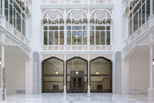 Bright white empty library hallway with skylight and lights hanging in corridor with carvings photo