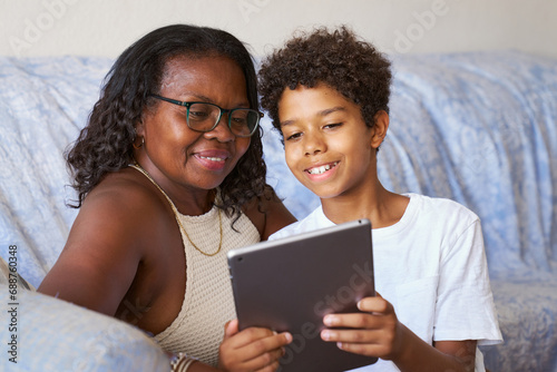 Grandson with grandmother using tablet photo