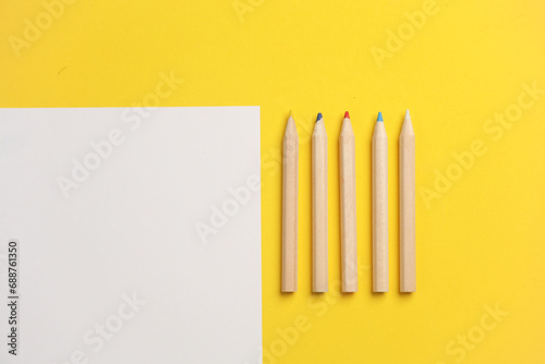 Wooden colored pencils and paper sheet on yelow background. Creativity  art