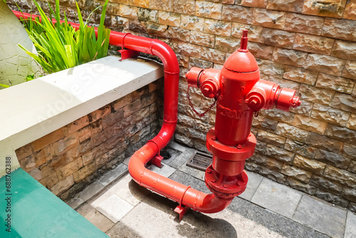 Red colored Hydrant pipe is a fire extinguisher system that is connected to a pressurized water source and distributes water to the extinguishing location. Hydrant for outdoor fire emergency. photo