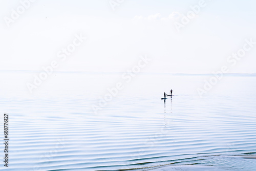 Two people are surfing on the calm waters of the sea. Togliatti, Russia - 30 Sep 2023