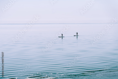 Two people are surfing on the calm waters of the sea. Togliatti, Russia - 30 Sep 2023 © KseniaJoyg