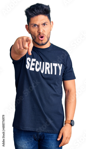 Handsome latin american young man wearing security t shirt pointing displeased and frustrated to the camera, angry and furious with you