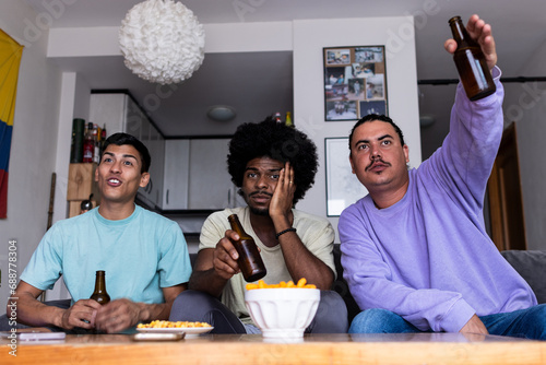 Male fans with beer watching match at home photo