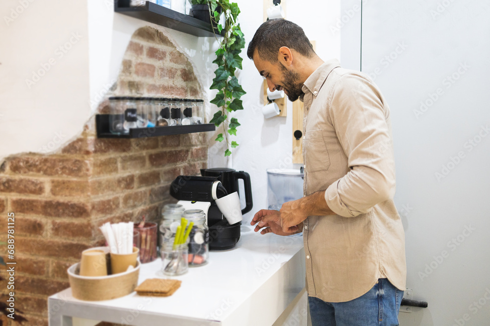 Businessman looking at coffee filling in mug at cafeteria Businessman looking at coffee filling in mug at cafeteria