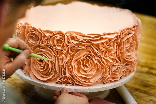 Close-up image of a beautiful cake being created, decorating a delicious cake with fondant roses photo