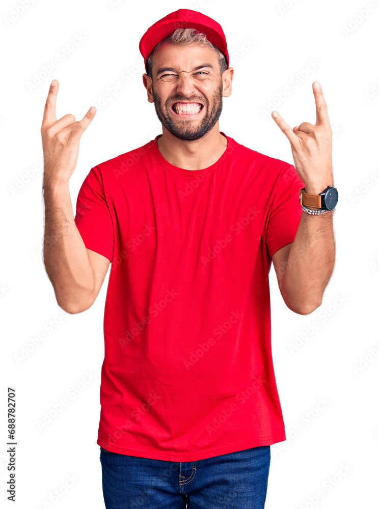 Young handsome blond man wearing t-shirt and cap shouting with crazy expression doing rock symbol with hands up. music star. heavy concept.