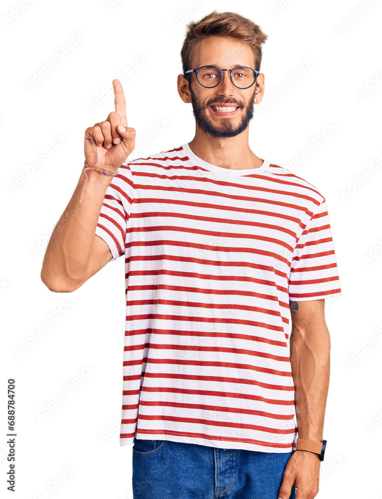 Fototapeta premium Handsome blond man with beard wearing casual clothes and glasses showing and pointing up with finger number one while smiling confident and happy.