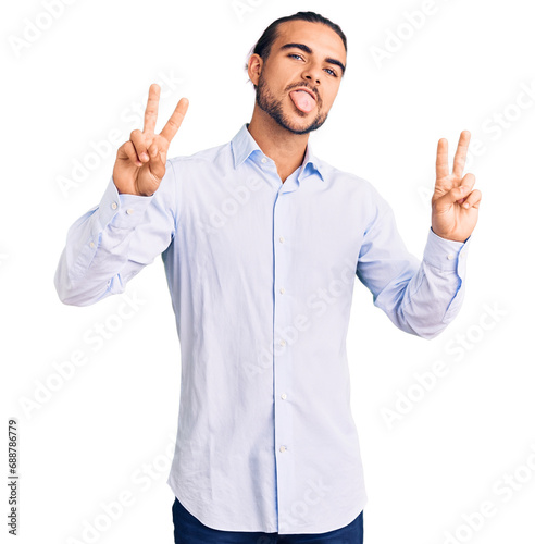 Young handsome man wearing business clothes smiling with tongue out showing fingers of both hands doing victory sign. number two.