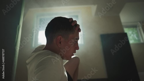 Fatigued man shakes sweat drenched hair taking pause from strenuous efforts to enhance endurance and strength. Tiredness and exhaustion from excessive involvement in active sports