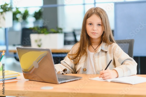 First day at school. Cute and happy little girl children using laptop computer, studying through online e-learning system