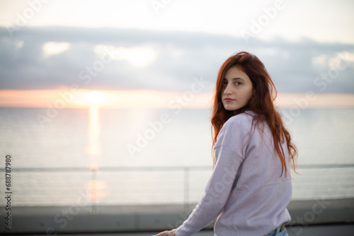 Young woman looking at camera in front of the sea at sunrise. © Carlos