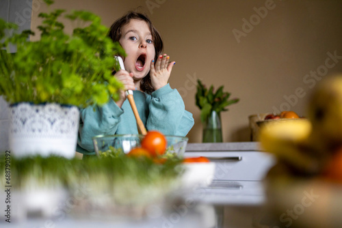 Socked female kid preparing salad at home photo