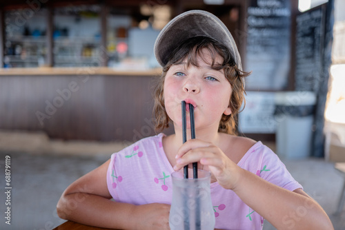 Child with straw in mouth sitting in cafe photo