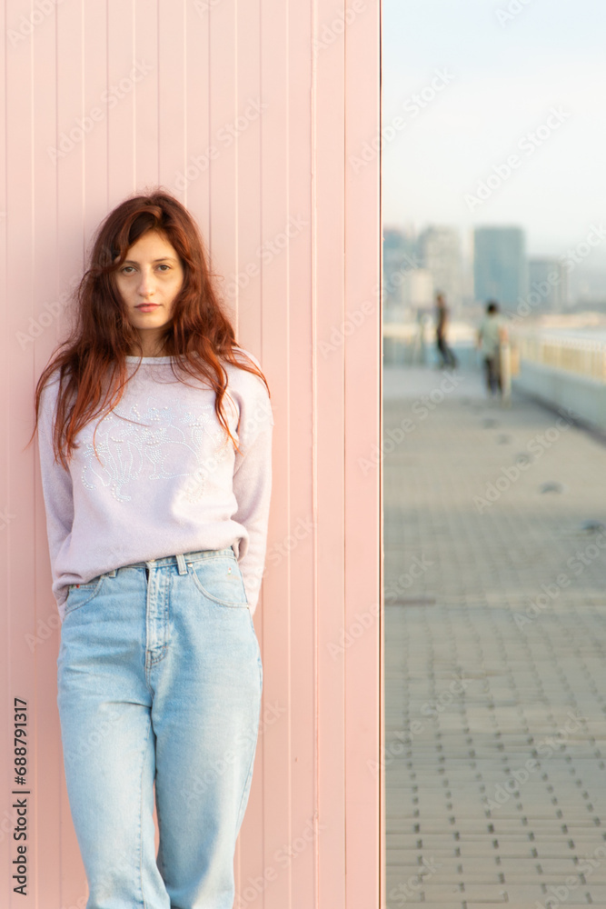 Young woman posing in front of the sea leaning against a pink wall Young woman posing in front of the sea leaning against a pink wall