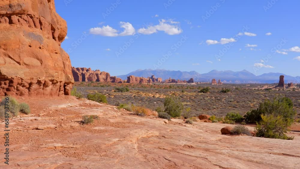 Establishing shot of mountain trail with red rocks background in Double Arch, Arches National Park, Utah, North America. Day time on October 2023. Still camera view. ProRes 422 HQ. Establishing shot of mountain trail with red rocks background in Double Arch, Arches National Park, Utah, North America. Day time on October 2023. Still camera view. ProRes 422 HQ.