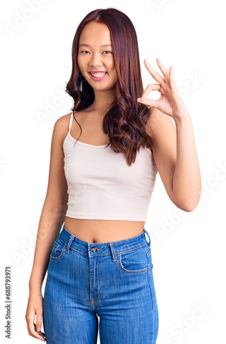 Young beautiful chinese girl wearing casual clothes smiling positive doing ok sign with hand and fingers. successful expression.