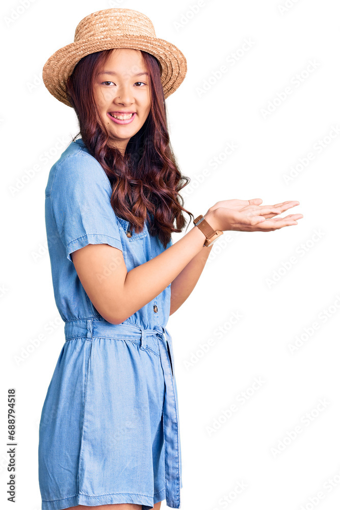 Young beautiful chinese girl wearing summer hat pointing aside with hands open palms showing copy space, presenting advertisement smiling excited happy Young beautiful chinese girl wearing summer hat pointing aside with hands open palms showing copy space, presenting advertisement smiling excited happy