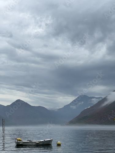 Fishing boat moored in the sea against the backdrop of high mountains in the fog