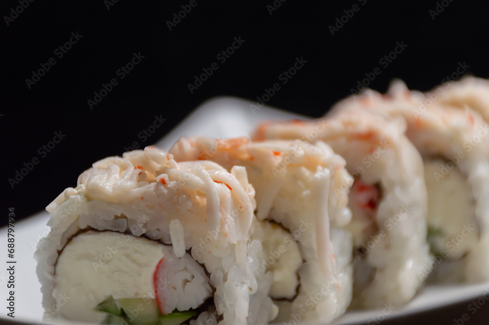 Japanese rolls on a white plate with a black background Japanese rolls on a white plate with a black background