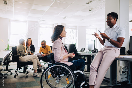 Businesswoman with disability listening to multiracial colleague at office. photo