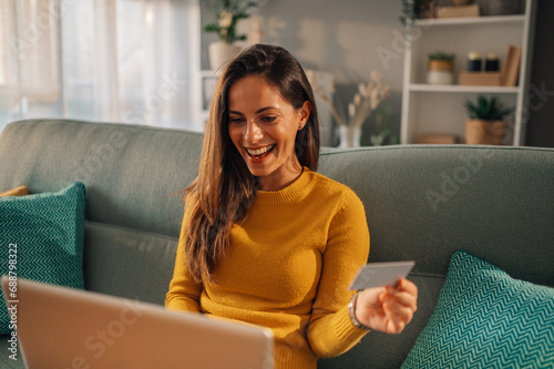 Принти на полотні A happy woman is checking on her bank account online on the laptop from home
