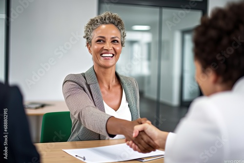 Fototapeta Naklejka Na Ścianę i Meble -  Happy business woman manager handshaking greeting client in office. Smiling female executive making successful deal with partner shaking hand at work standing at meeting table.